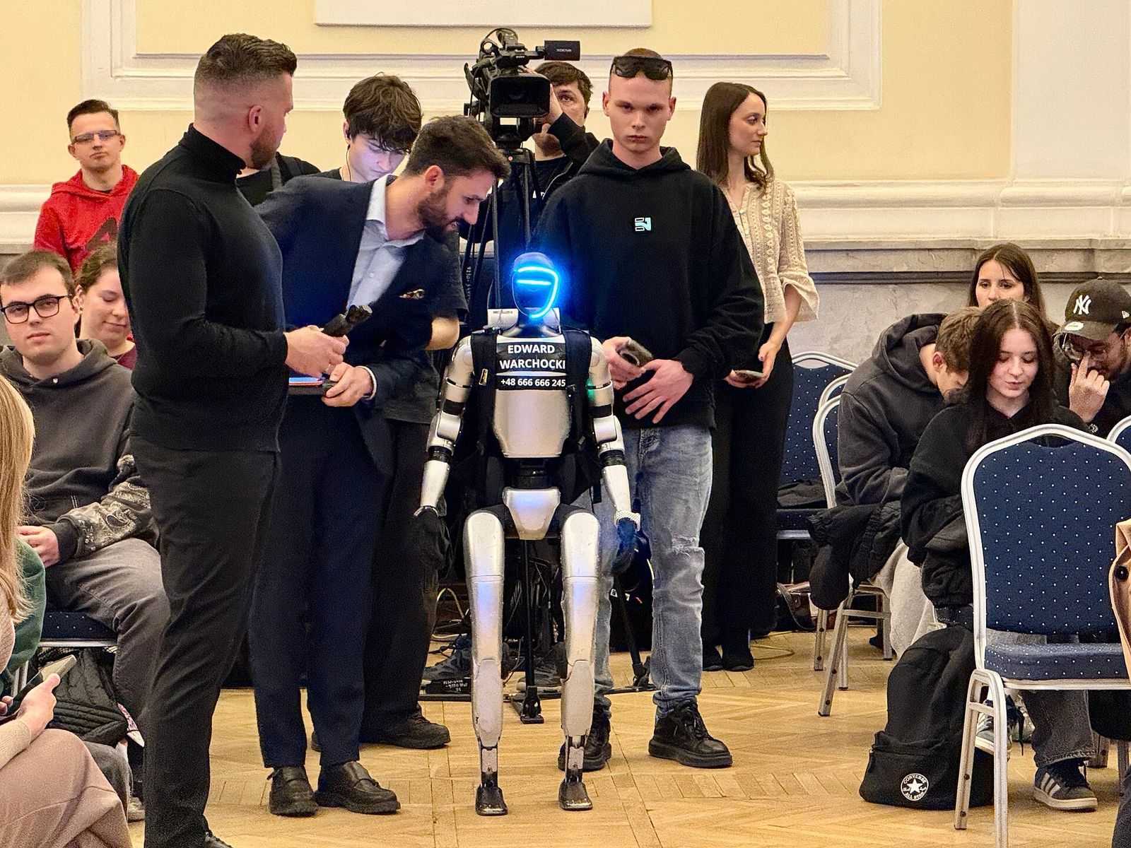 Robot hình người dựa trên Unitree G1 giữa khán giả và các ekip quay phim
